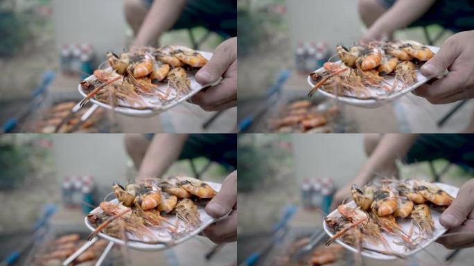 将一只烧焦的大虾放在一个人手中的盘子上，准备食用。