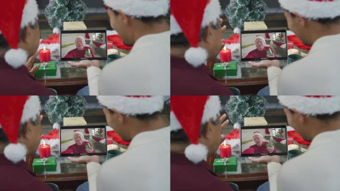带有圣诞老人帽子的混血儿父子使用平板电脑进行圣诞节视频通话，屏幕上有男人