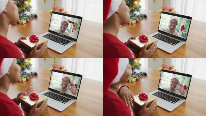 戴着圣诞老人帽子的非裔美国妇女使用笔记本电脑进行圣诞节视频通话，屏幕上有男子