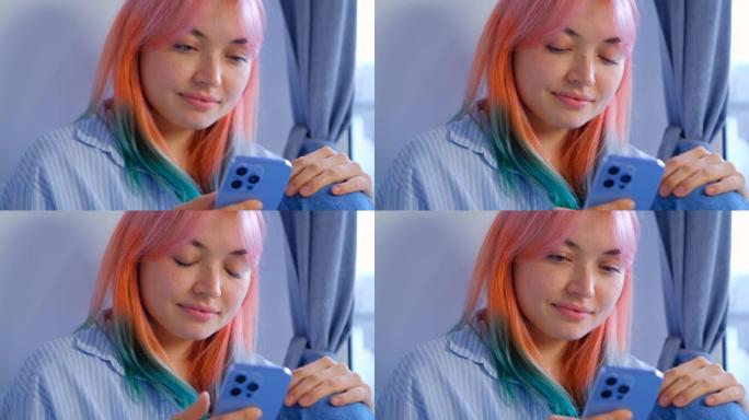 手机上有染头发的女孩浏览社交媒体新闻提要的视频。可爱的年轻女子，有色粉色头发，用现代智能手机上网