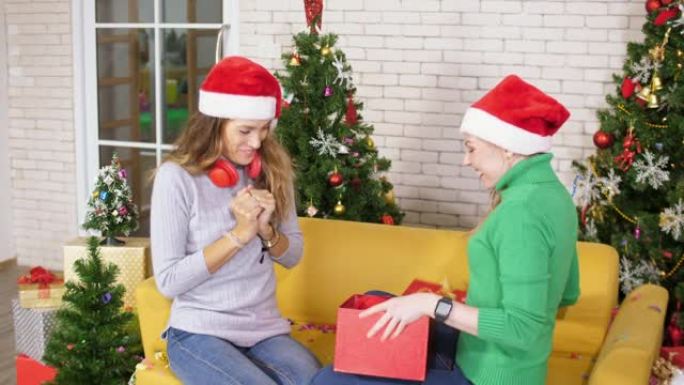 快乐的高加索女人和她的朋友打开礼品盒，圣诞部分概念
