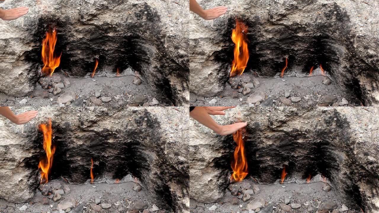 女人在土耳其Chimaera山永远燃烧的大火中温暖双手
