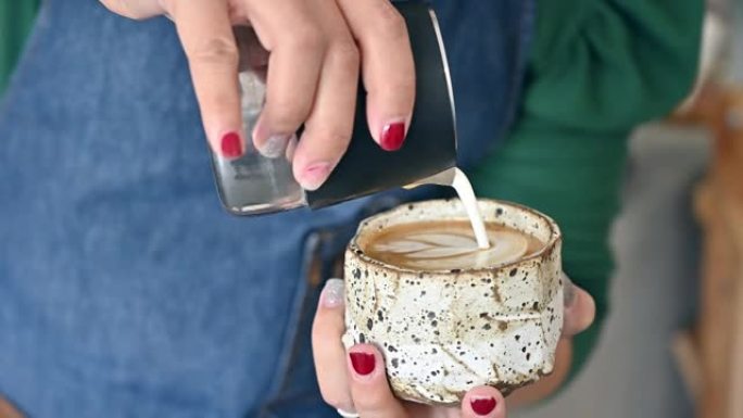 女性咖啡师试图将蒸牛奶倒入浓缩咖啡以制作拿铁艺术的视频。