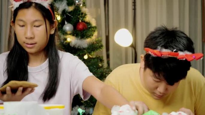 亚洲儿童在晚上在家一起制作姜饼屋，圣诞节庆祝生活方式。