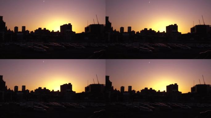 日落风景与城市的建筑轮廓。焦点在正面，背景模糊。镜头轻微晃动。天空的色温是黄色和紫色。