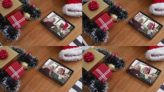 在平板电脑上的圣诞节视频通话中，戴着圣诞老人帽子的白人父亲和儿子微笑