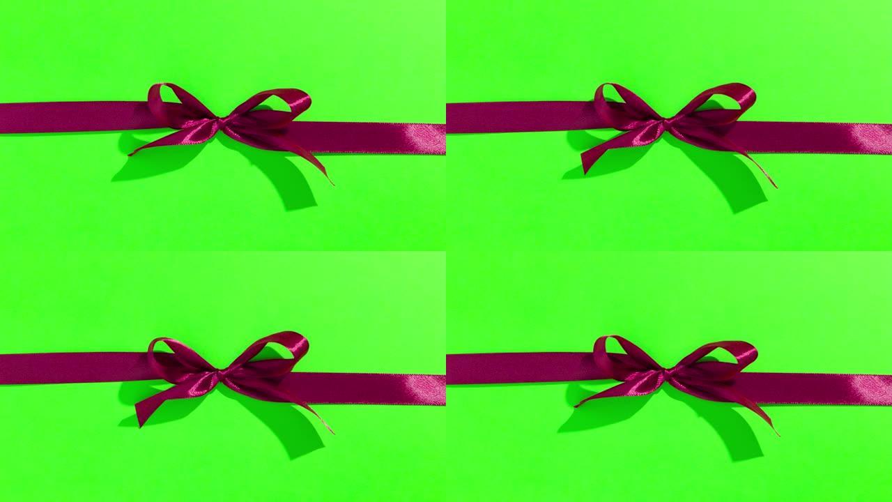 绿色屏幕上带有蝴蝶结的红丝带，打开并打开礼物，顶视图-情人节，圣诞节的定格动画。