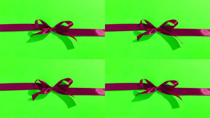 绿色屏幕上带有蝴蝶结的红丝带，打开并打开礼物，顶视图-情人节，圣诞节的定格动画。
