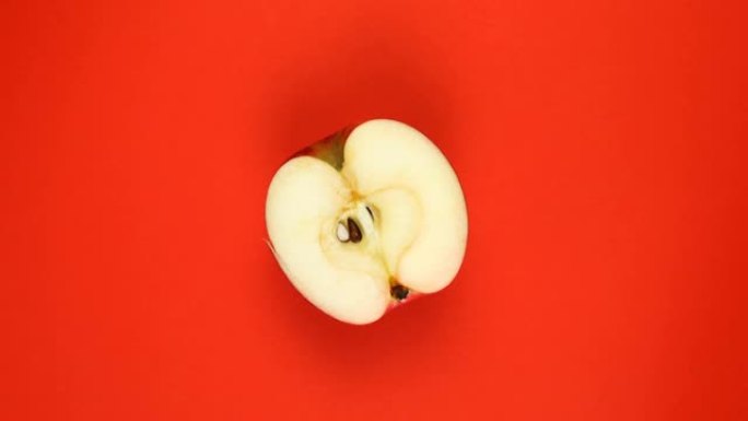 俯视图: 一半的苹果在红色表面上旋转-慢动作