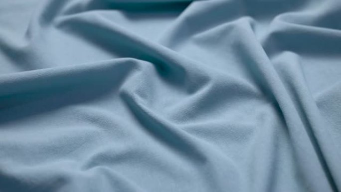 织物布背景。纹理棉纺织材料特写。裁缝桌上的蓝色波浪状褶皱织物