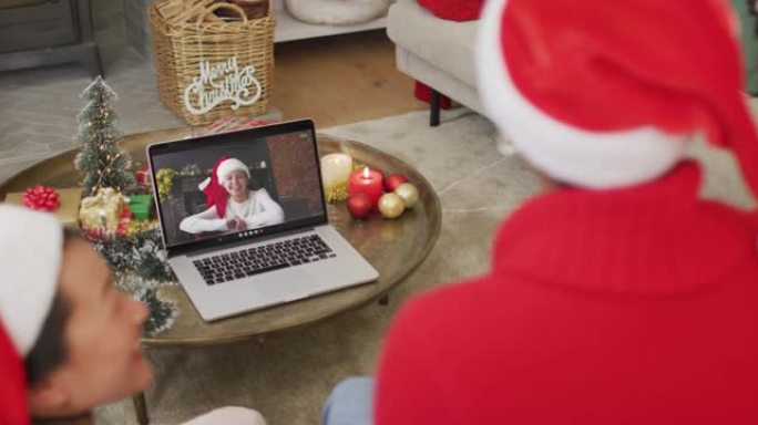 拥有圣诞老人帽子的多元化家庭使用笔记本电脑进行圣诞节视频通话，屏幕上有幸福女人