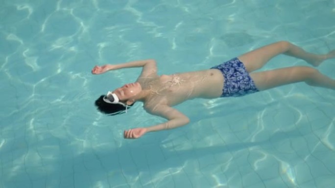 快乐的亚洲男孩在度假期间漂浮在游泳池里，在酒店或度假村里，带着家庭生活方式的概念。