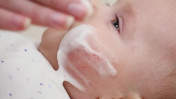 母亲使用医用软膏治疗婴儿皮炎和痤疮的特写镜头。新生婴儿卫生、健康和皮肤护理的概念