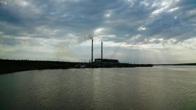 环境污染。在行业背景下飞越河水。河岸的有害工厂。工业烟囱与傍晚的蓝天形成鲜明对比。