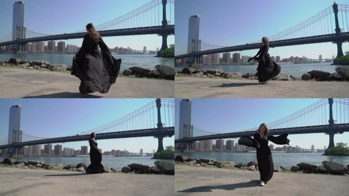 一位身穿黑色长裙的年轻女子走在美国纽约曼哈顿桥附近