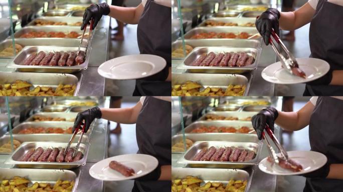 在公共食堂或自助餐中，服务员为那盘美味的烤肉香肠服务。没有脸。