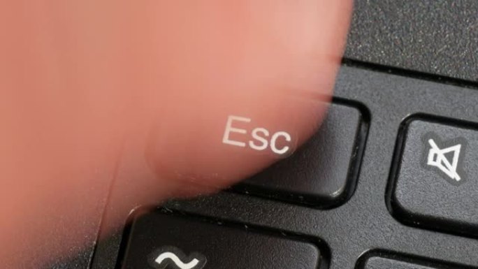 男子按下笔记本电脑键盘上的esc escape键，手指，宏，细节，极端特写。停止，停止，逃避序列，退