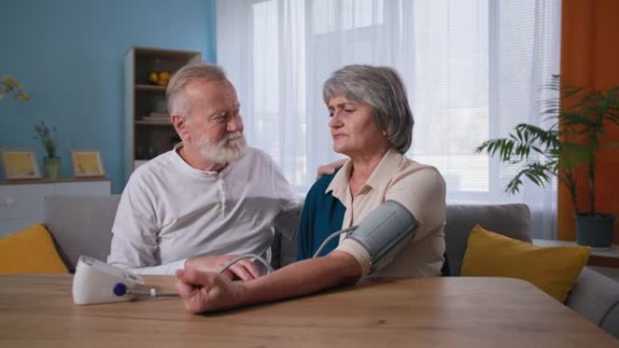 支持和护理，老年夫妇使用血压监测仪对家中患有高血压的妻子