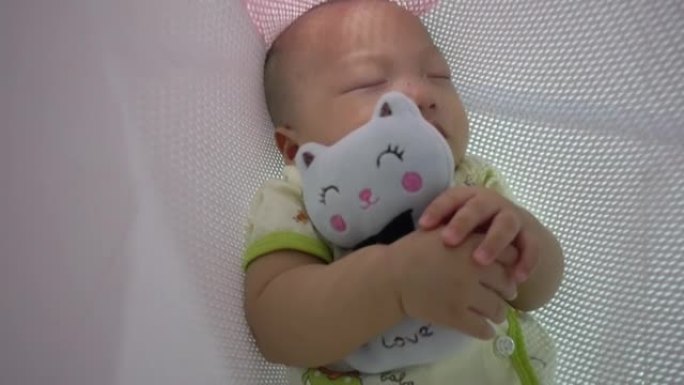 可爱的中国光头宝宝抱着猫毛绒玩具睡觉