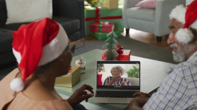 快乐的非洲裔美国高级夫妇在圣诞节与女性朋友进行笔记本电脑视频通话