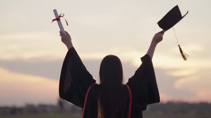 毕业于大学的女学生站在日落的户外时间，毕业于剪影日落概念。