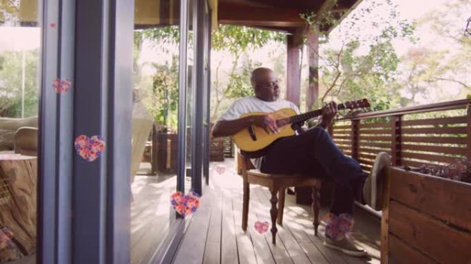 在家里的露台上弹吉他的高级非洲裔美国人身上的粉红色花朵动画