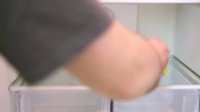 一个男人用黄色海绵的手洗冰箱