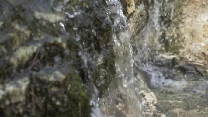 山区的水晶瀑布，光滑的水滴落在slo-mo的苔藓石头上