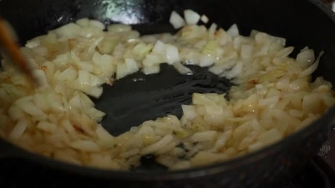 用油在平底锅里煎洋葱。用木铲在煎锅中搅拌洋葱