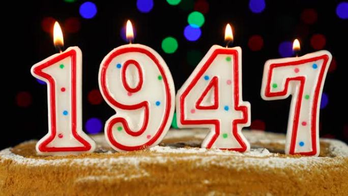 生日蛋糕与白色燃烧的蜡烛在数字1947的形式