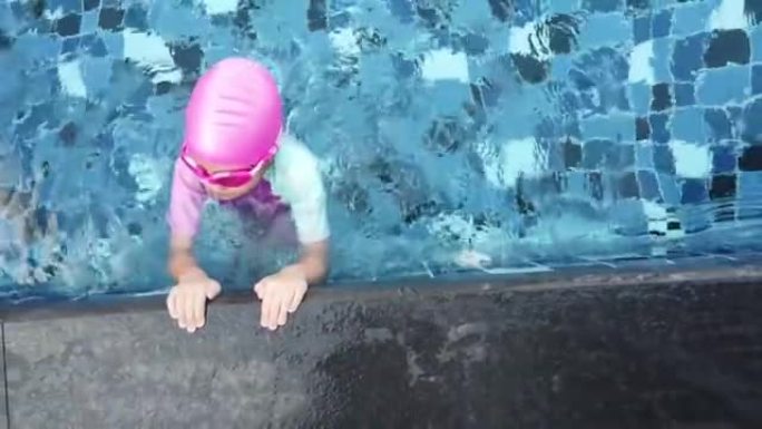 小女孩正在游泳池边练习潜水。