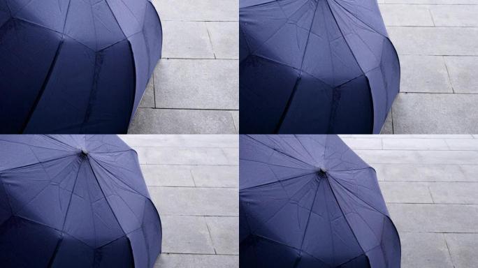 雨天用水滴收上雨伞。从下到上倾斜镜头。主题在左边。
