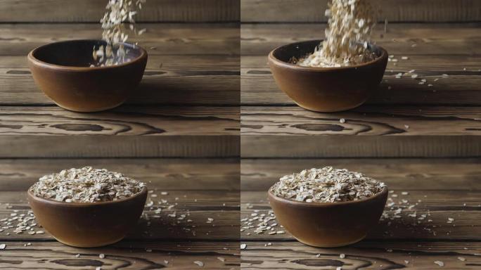 燕麦片的慢动作掉入木桌上的碗中。健康的生活理念，清洁食品，饮食。早餐