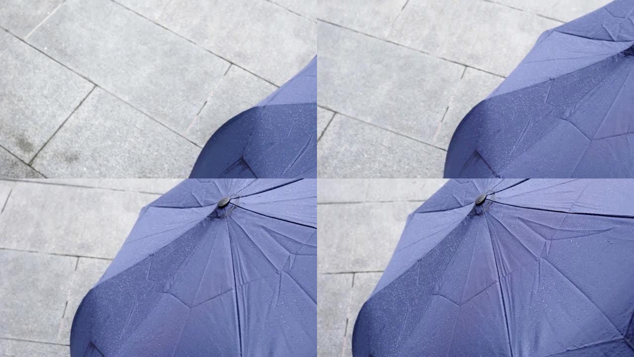 雨天用水滴收上雨伞。从左到右倾斜镜头。主题在右边。
