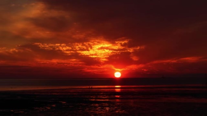 红日飘过云层和海水泥滩