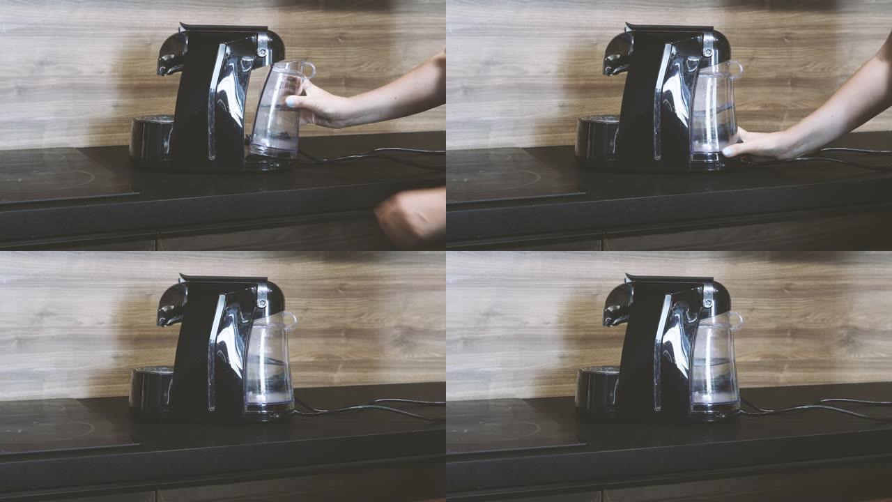 女性手的特写镜头将装有清水的塑料过滤容器插入胶囊咖啡机中。为咖啡机注水