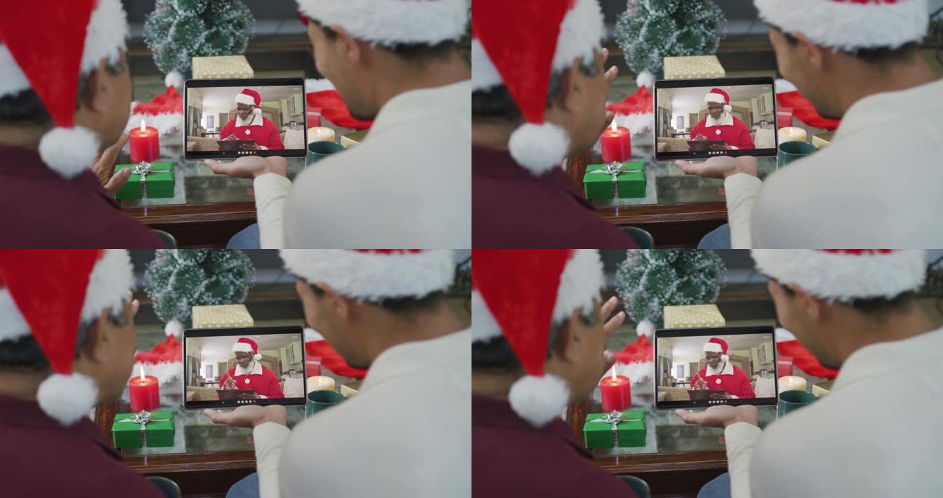 带有圣诞老人帽子的混血儿父子使用平板电脑进行圣诞视频通话屏幕上的圣诞老人