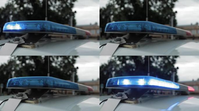 一名警官在巡逻车顶上闪灯。警车闪烁红色和蓝色。