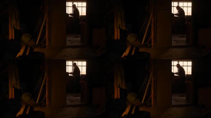 老人在阁楼阁楼的房子窗户上戴眼镜看书。古老的古董古董楼上阁楼