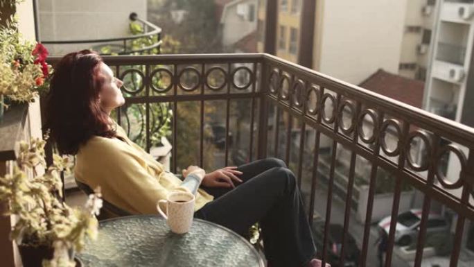 成熟的女人早上在阳台上放松