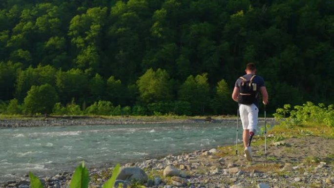男性残疾旅行者独自一人在山河岸上行走