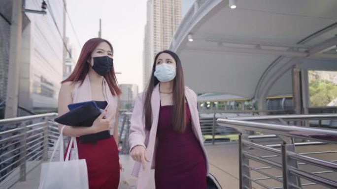 两名年轻的职业女性步行与城市城市商业环境周围一起工作，实习公司员工，亚洲职业女性携带办公室文件和工作