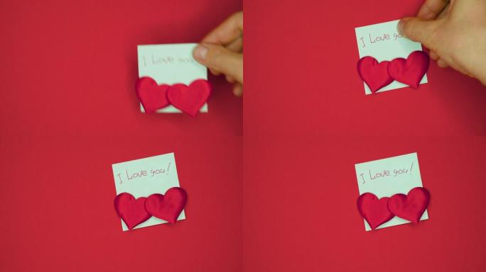 男手在贴写有我爱你的字的贴纸，用笔写的，红底贴了两颗情人节的心