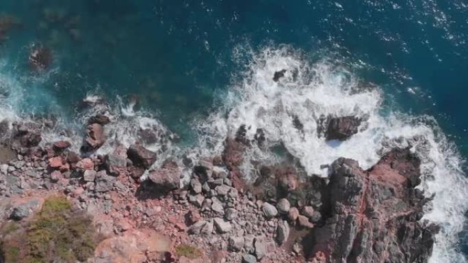 多岩石的海岸线和海浪。巨大的海浪在海边的岩石边缘破裂，飞溅并产生白色泡沫。汹涌的海浪和令人惊叹的岩石