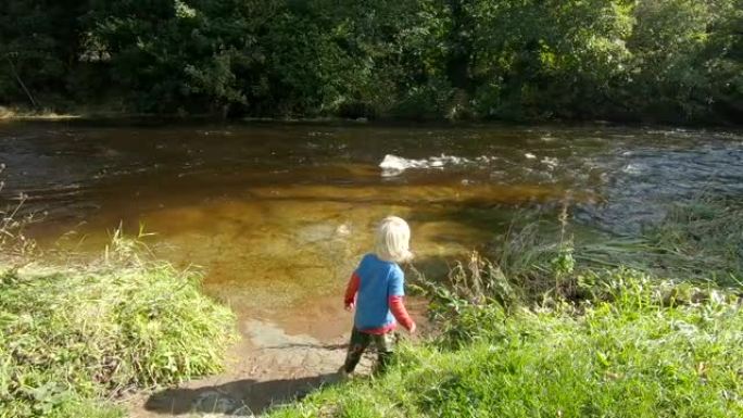可爱的小男孩把棍子扔进急流的浅河，慢动作
