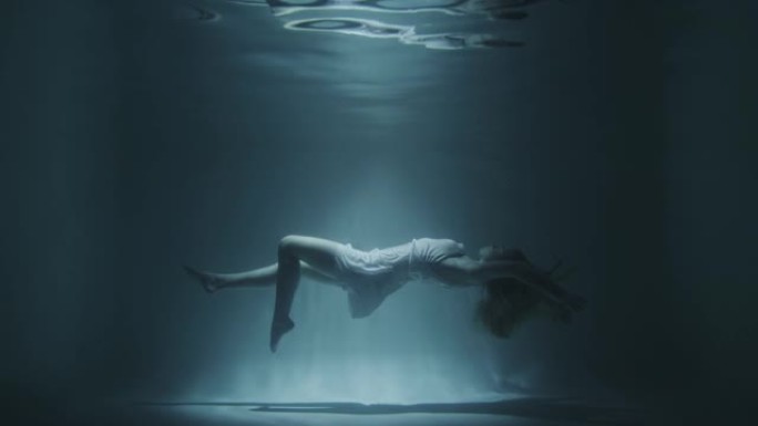 穿着白色连衣裙的女孩在水下游泳