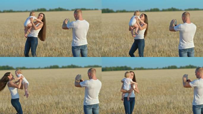 当一个美丽的女人围着一个婴儿时，年轻人在手机上拍摄了一段视频。在麦田里拍照，一位博主制作了一段视频。