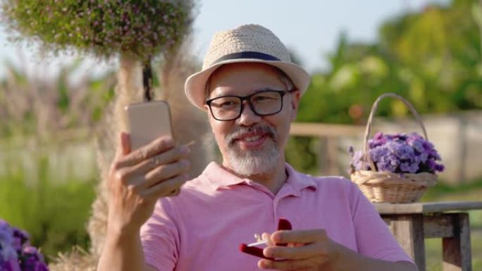 惊讶。在线视频通话，快乐的亚洲灰胡子男人戴眼镜向笔记本电脑上的女朋友求婚
