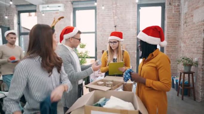 办公室里的现代多种族同事，打包衣服和食物，用于圣诞节捐赠