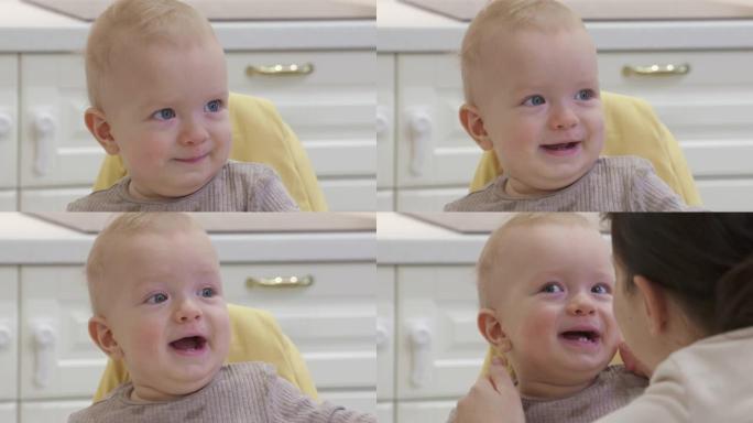 快乐的妈妈带着微笑的宝宝在家，慈爱的妈妈挤压宝宝的脸颊，8个月大的高加索孩子的脸特写。